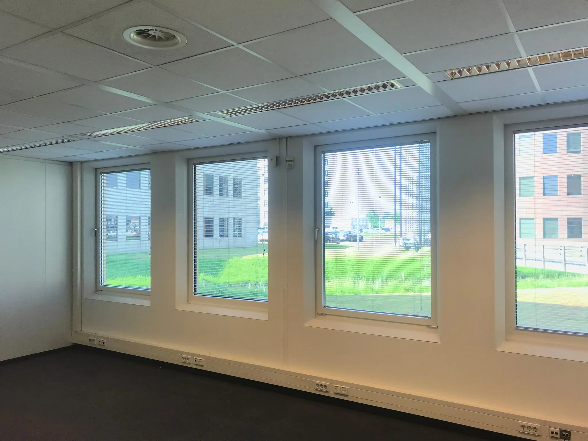 Leeg kantoorruimte met systeemplafond en grote ramen met uitzicht op kantoorpanden aan het Rivium Quadrant.